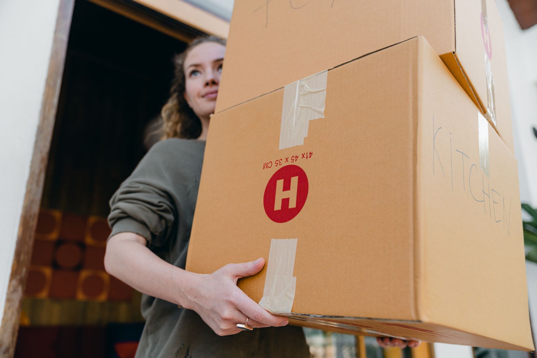 personne qui porte des cartons en sortant d'un logement en cours de déménagement